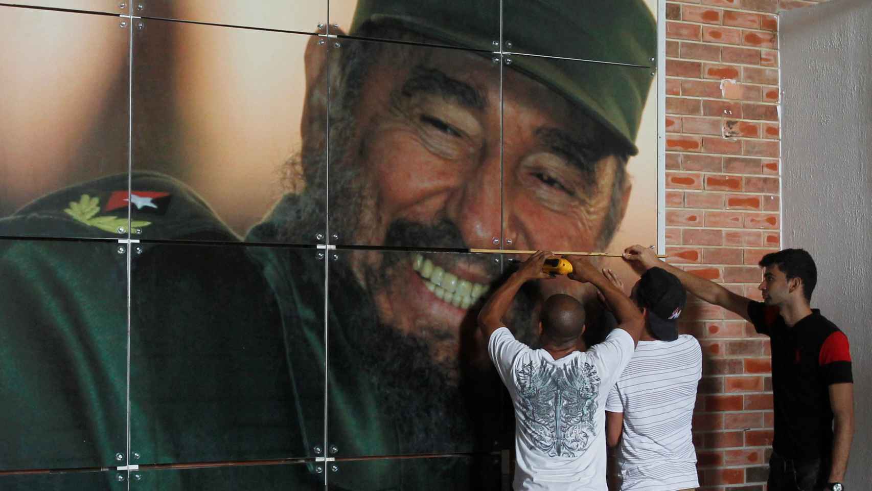 Unos trabajadores instalan un mural del expresidente cubano para la exposición por su 90 cumpleaños.