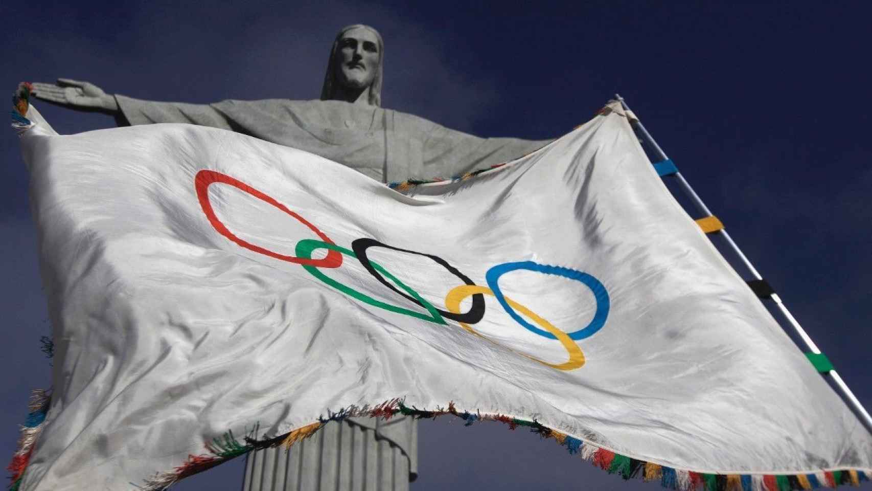 La bandera olímpica ondea delante del Cristo del Corcovado.