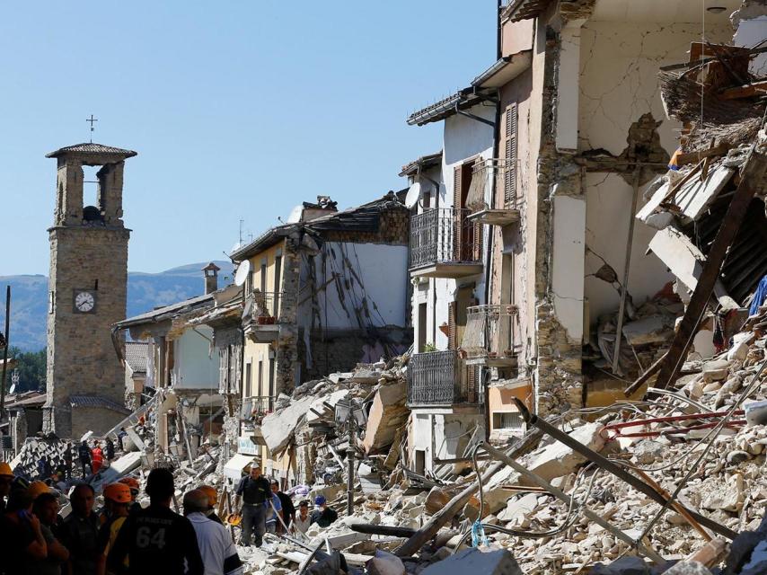 Personas que observan los edificios derruidos después del terremoto en  Amatrice.