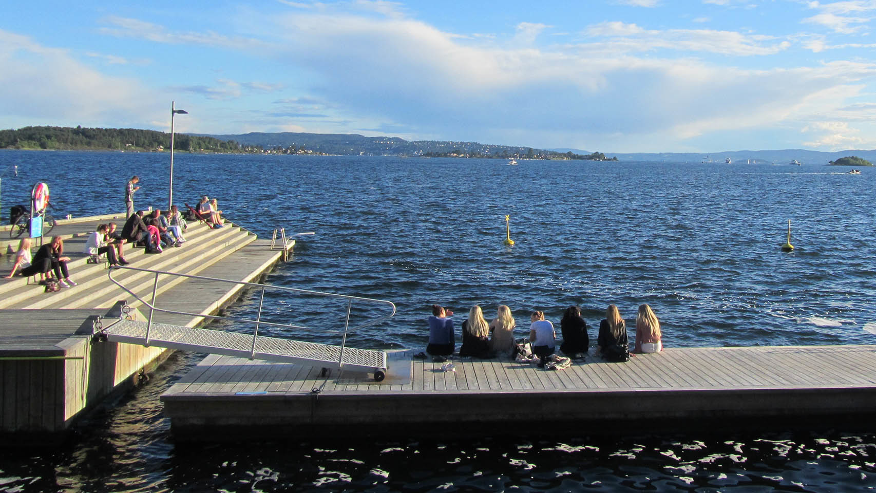 Jóvenes disfrutan de la tranquilidad del fiordo y las vistas desde el puerto.