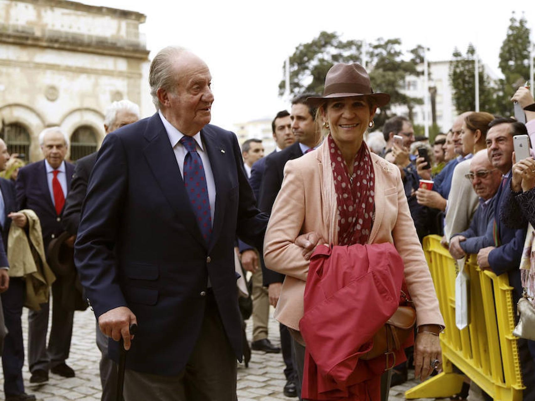 Juan Carlos se apoya en la infanta Elena para caminar, mientras se acompaña de una muleta.