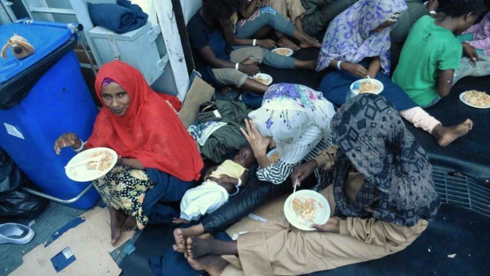 Mujeres y niños comen a bordo de la Reina Sofía tras el último rescate.