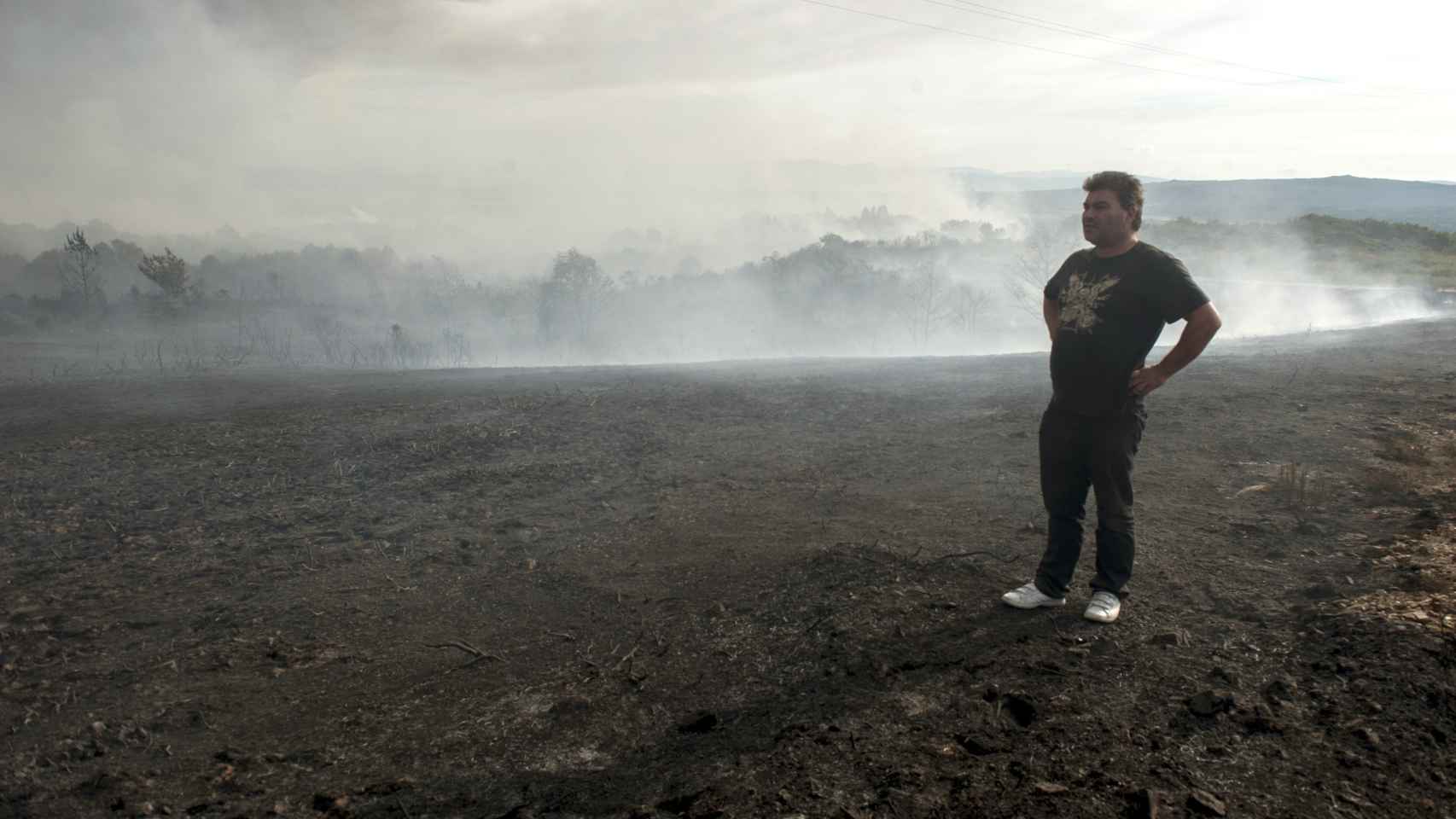 Un hombre observa la zona afectada por el incendio de Xunqueira de Ambía.