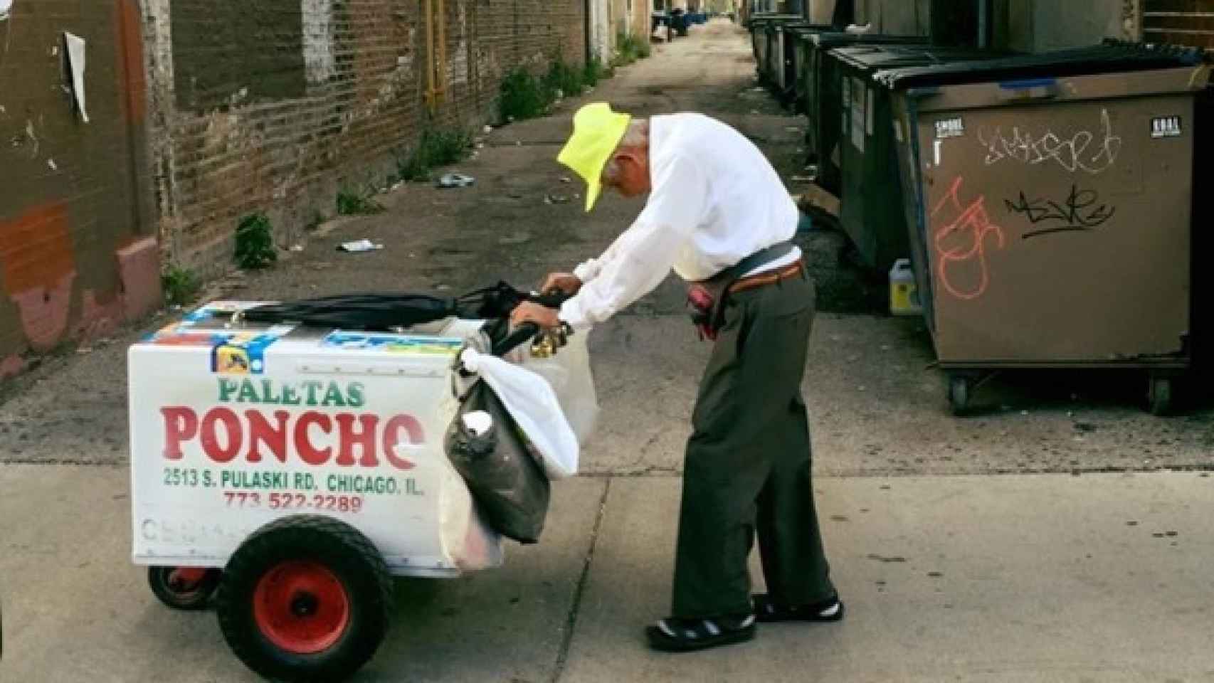 Fidencio arrastrando su carrito de helados con su característica gorra amarilla.