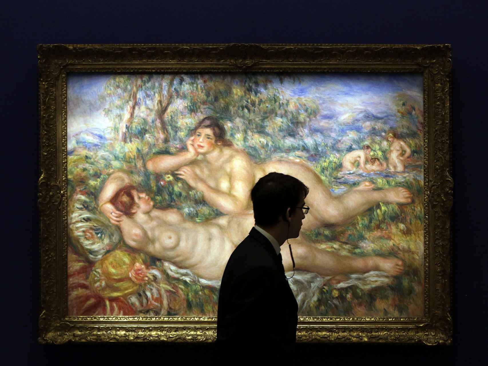 Un vigilante pasa ante la obra Les baigneuses (1919), de Auguste Renoir, que se muestra en la exposición.