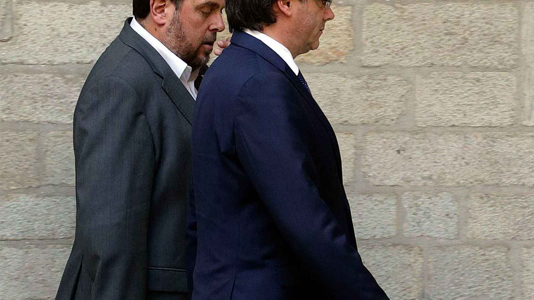 Puigdemont (en primer plano) y Junqueras hablando con él en una imagen de hace un año.