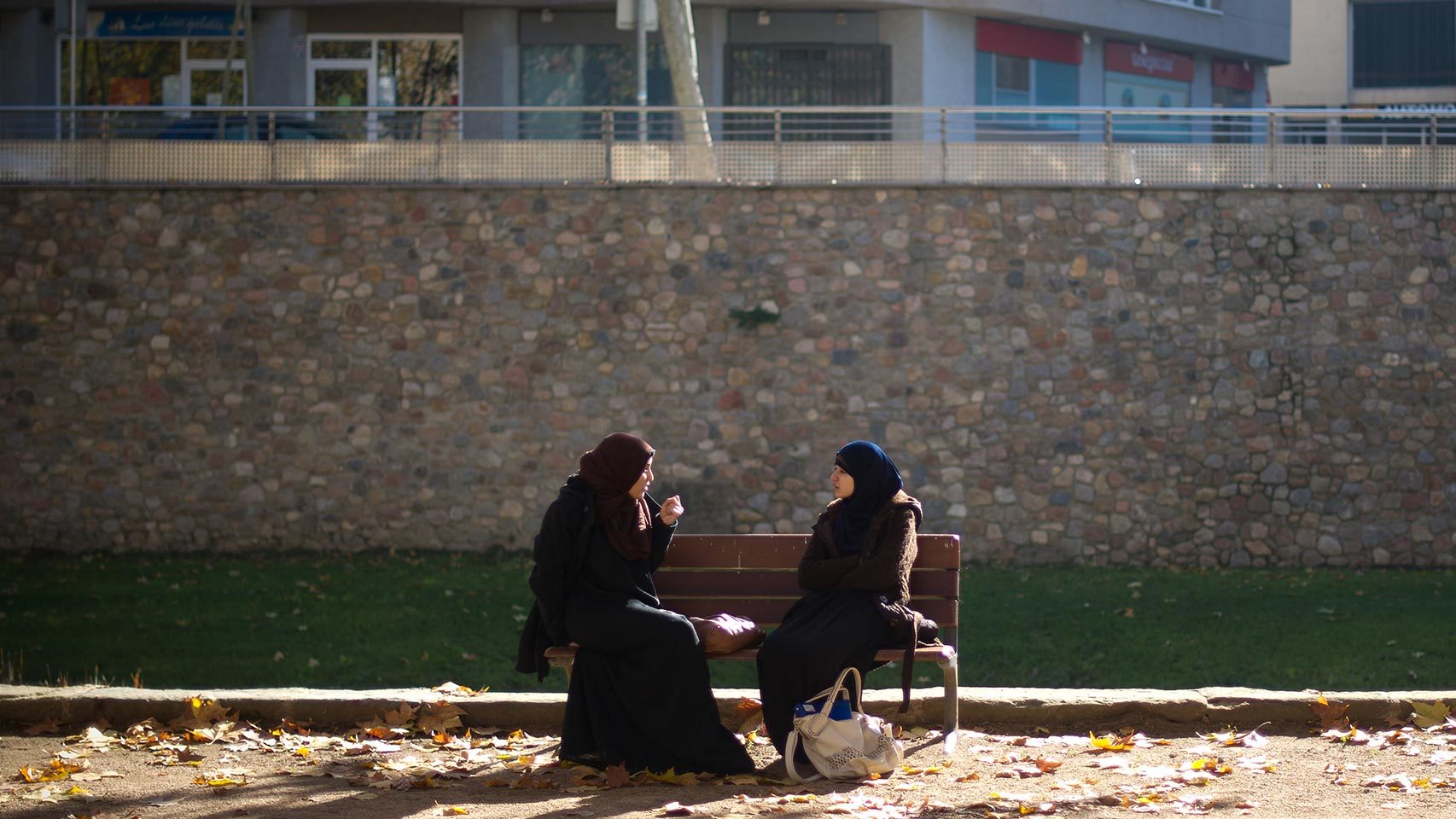 Dos mujeres con hiyab, sentadas en un banco.