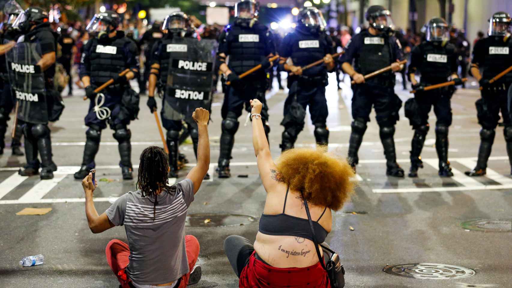 Dos mujeres protestan ante el cordón policial en Charlotte.