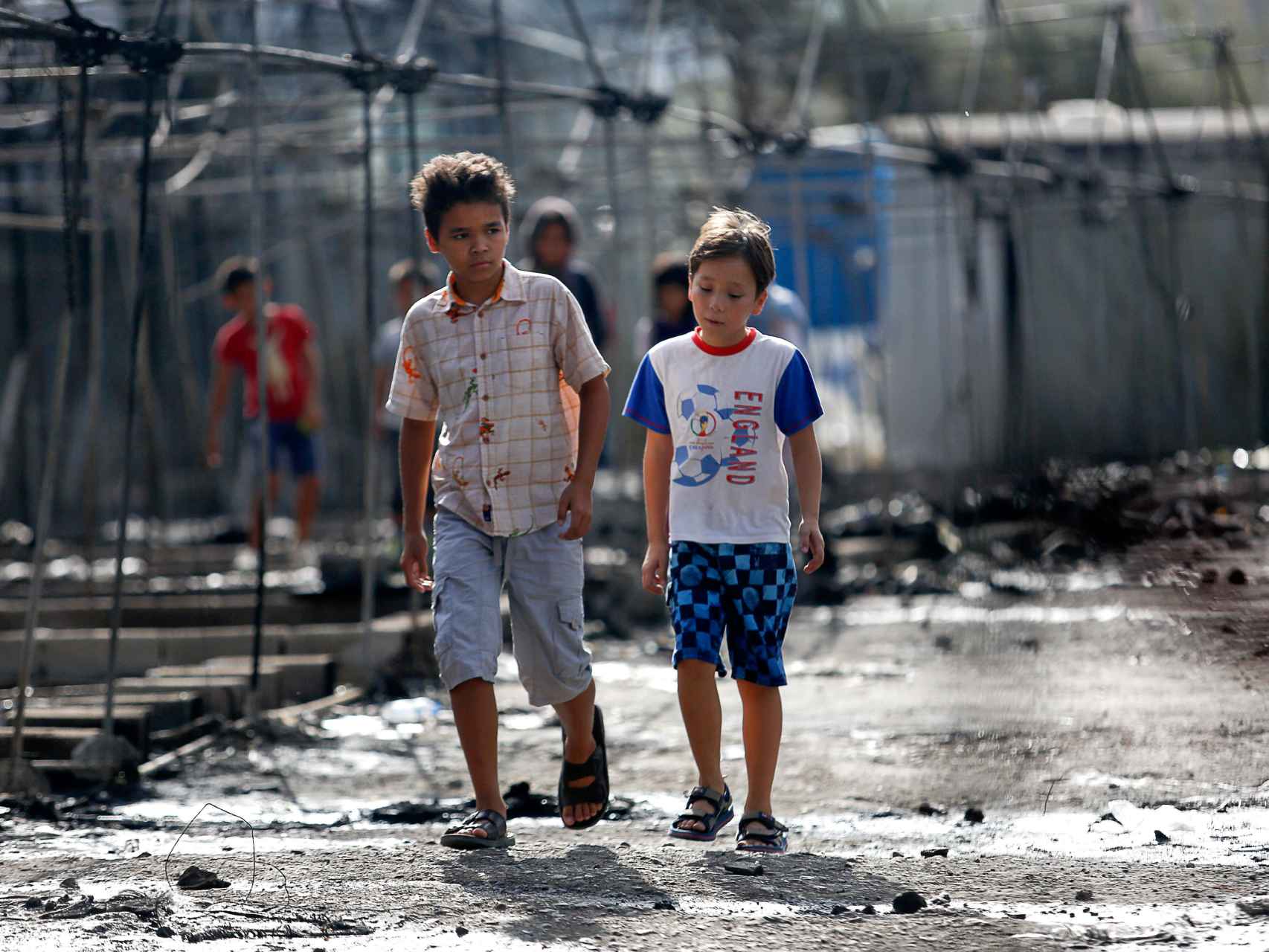 Unos niños caminan entre las cenizas de las casetas en el campo de Moria (Grecia) tras el fuego.