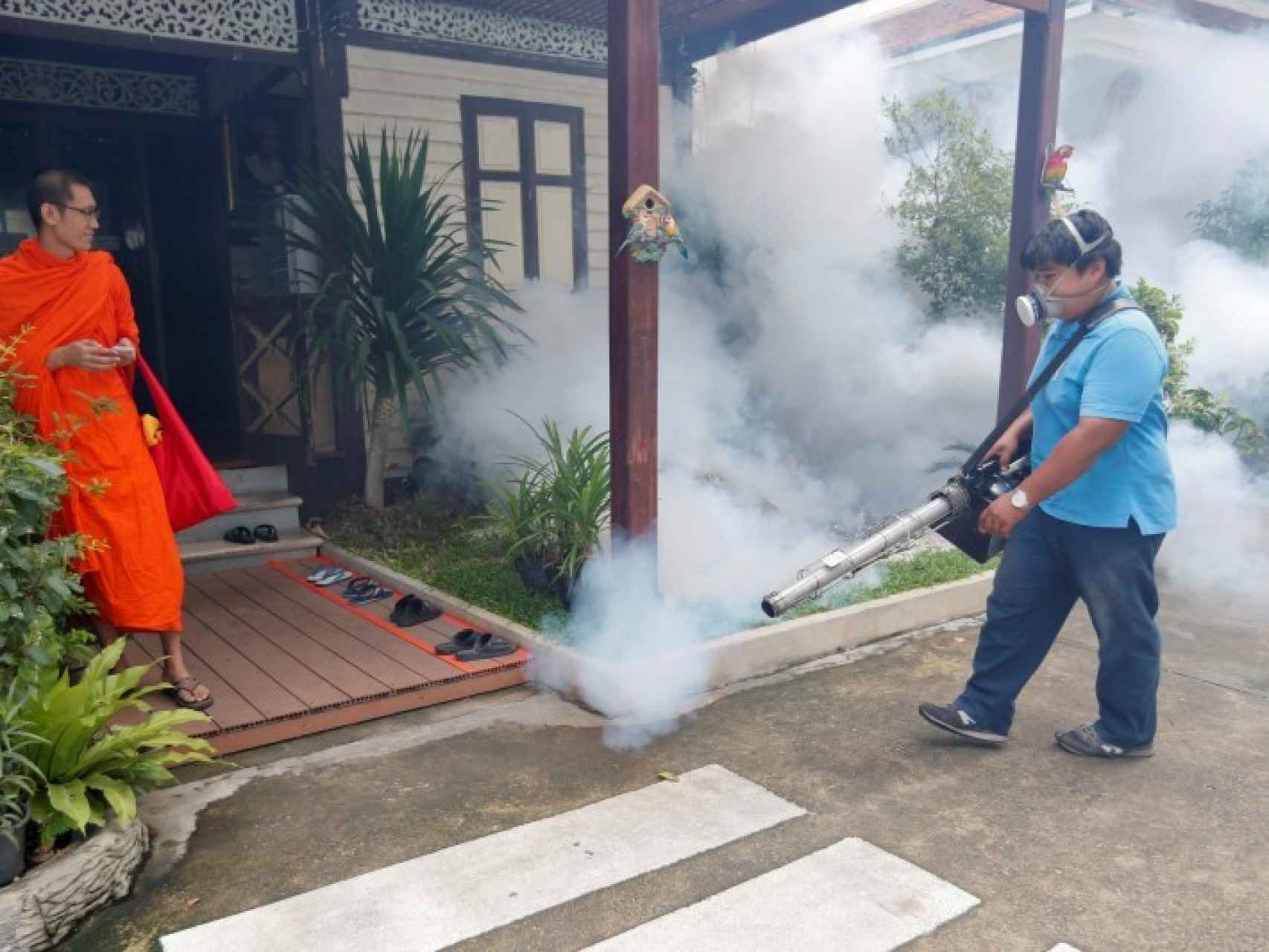 Un funcionario fumiga la entrada de un templo budista para combatir los mosquitos.