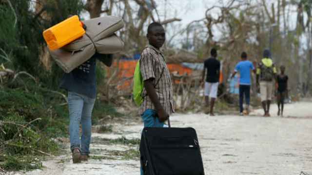 Varios haitianos transportan sus pertenencias.