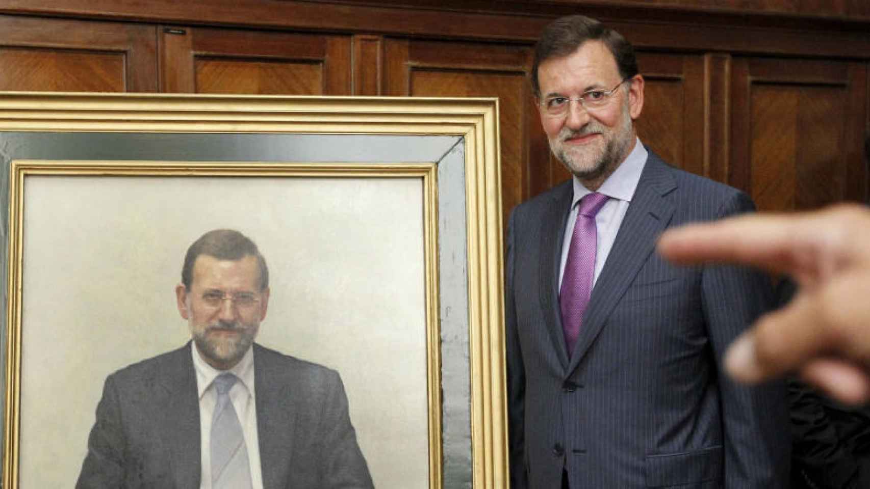 Mariano Rajoy posa junto a su retrato cuando fue ministro de Educación/ Efe