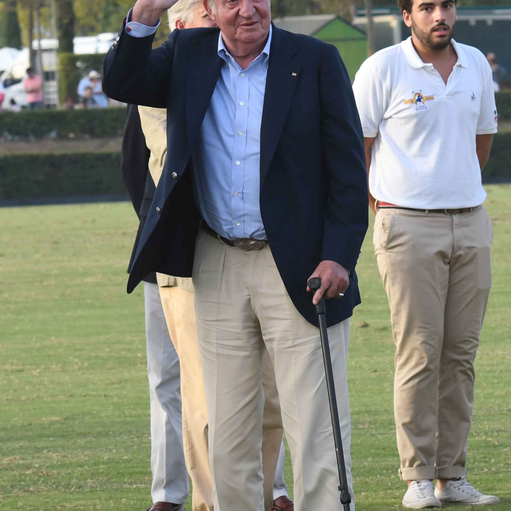 El rey Juan Carlos camina ayudado por un bastón.
