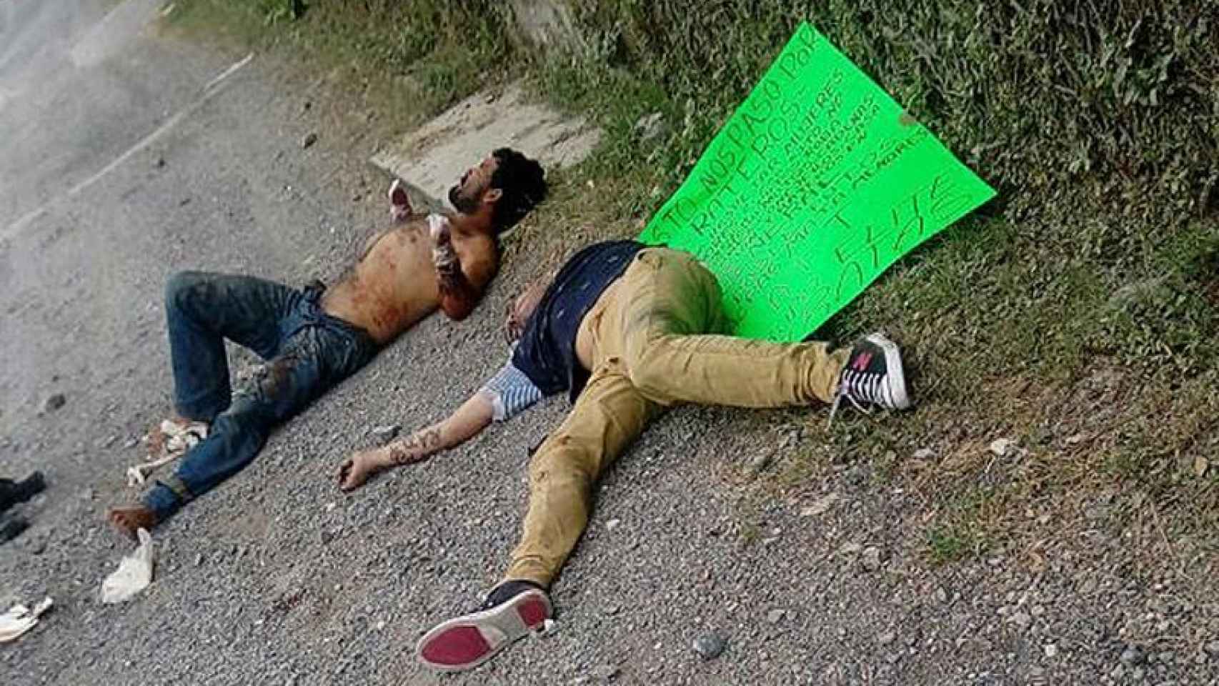 El fallecido y un superviviente yacen junto al cartel que pretende justificar la agresión.