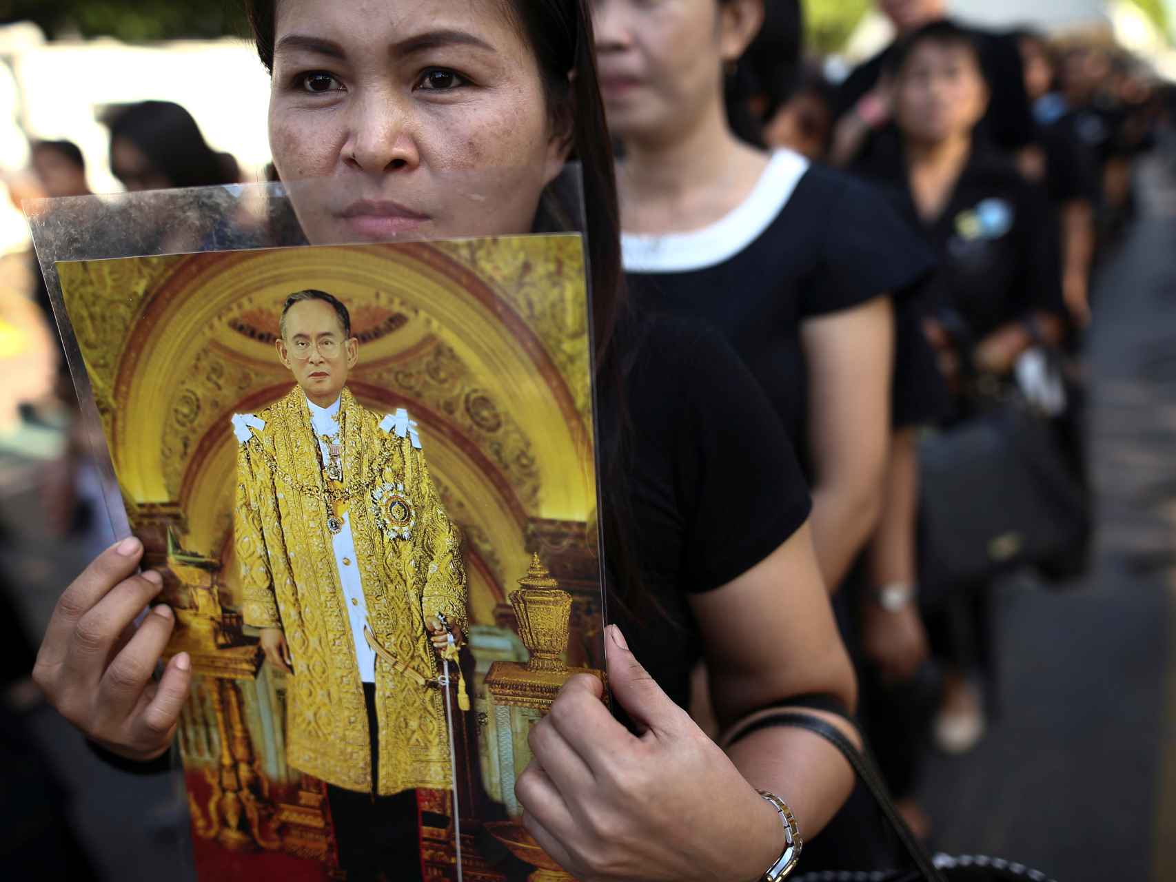Una mujer sostiene un retrato del monarca mientras espera para prestar sus condolencias en el Gran Palacio de Bangkok.