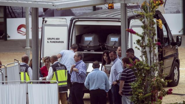 Operarios de una funeraria introducen en el coche fúnebre el cuerpo de la persona fallecida.