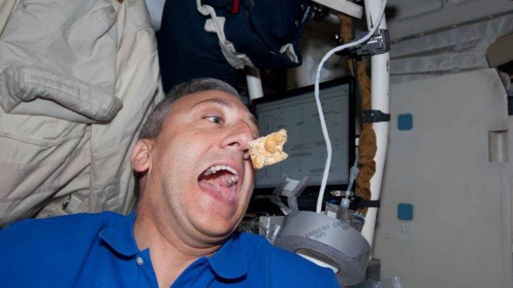 El astronauta tratando de dar un bocado en la ISS.
