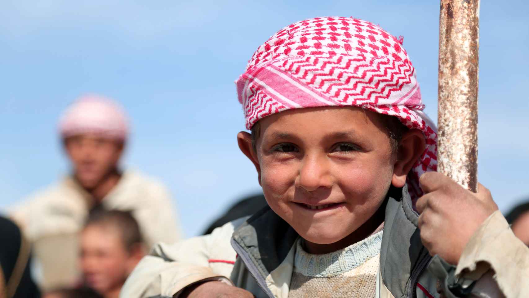 Un niño de la provincia de Raqa sonríe junto a otras personas que se desplazan lejos del fuego.