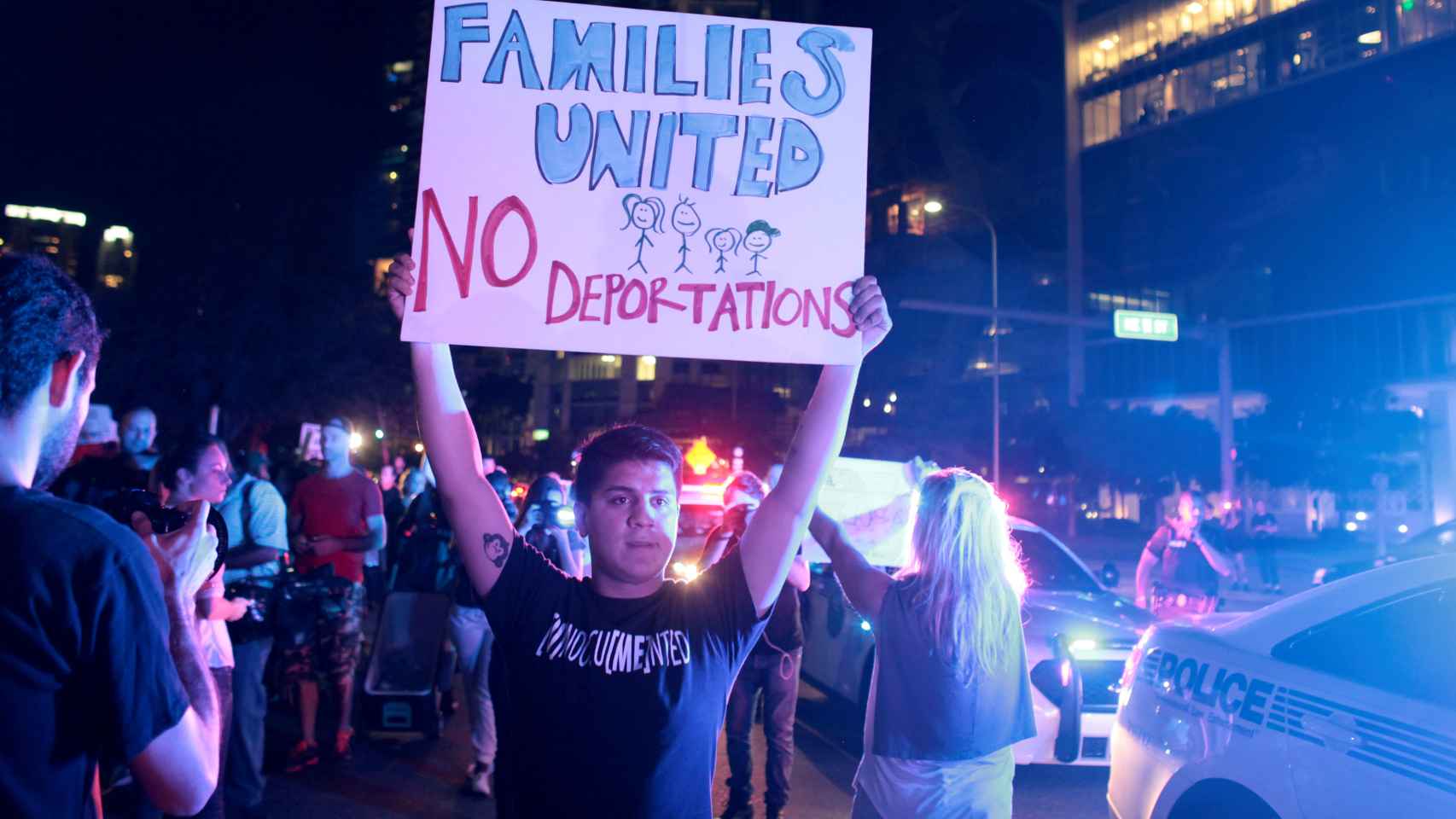 Un joven sostiene una pancarta contra las deportaciones en la tercera noche de manifestaciones contra Trump en Miami