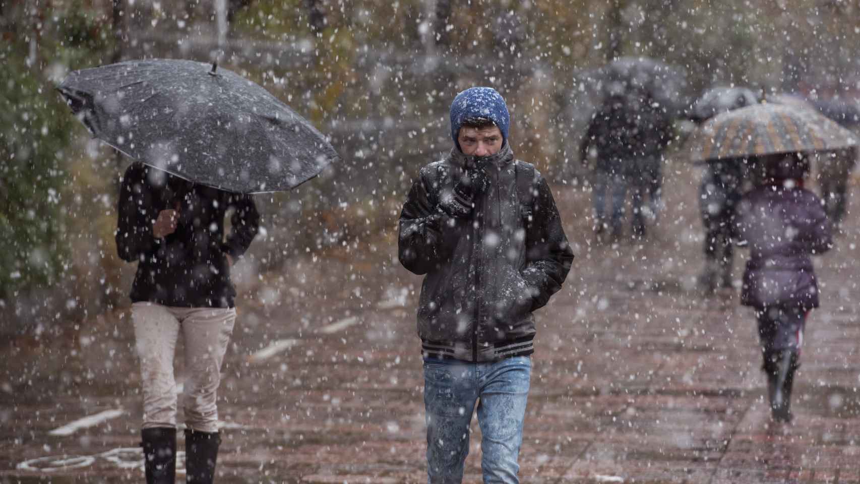Un joven intenta protegerse de la nevada por las calles de Vitoria.