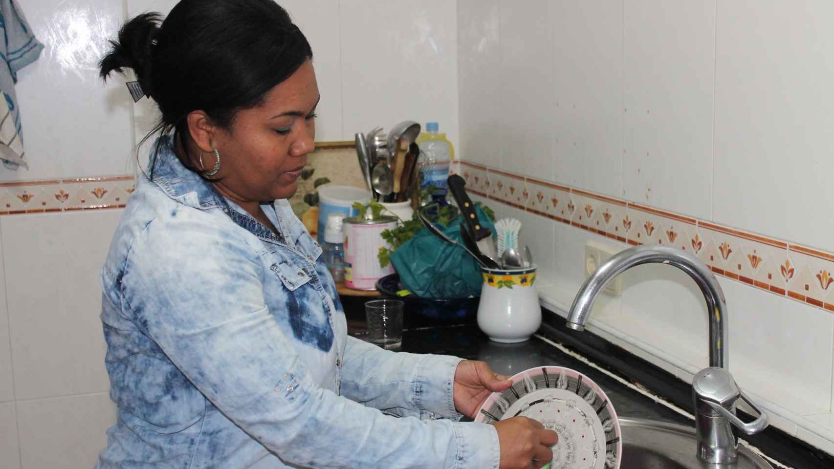 Juliana lava los platos en la cocina del piso que ocupa tras ser desahuciada de su domicilio
