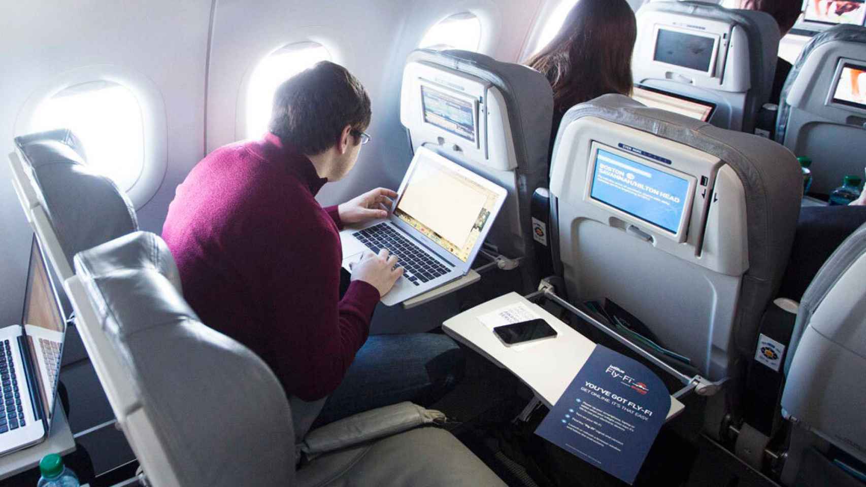 Un pasajero con su portátil en un avión.