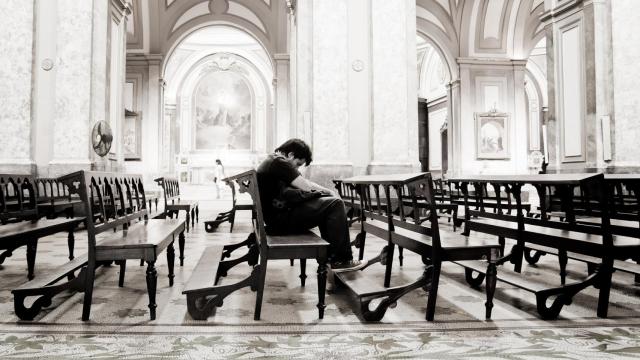 Un hombre reza en soledad.