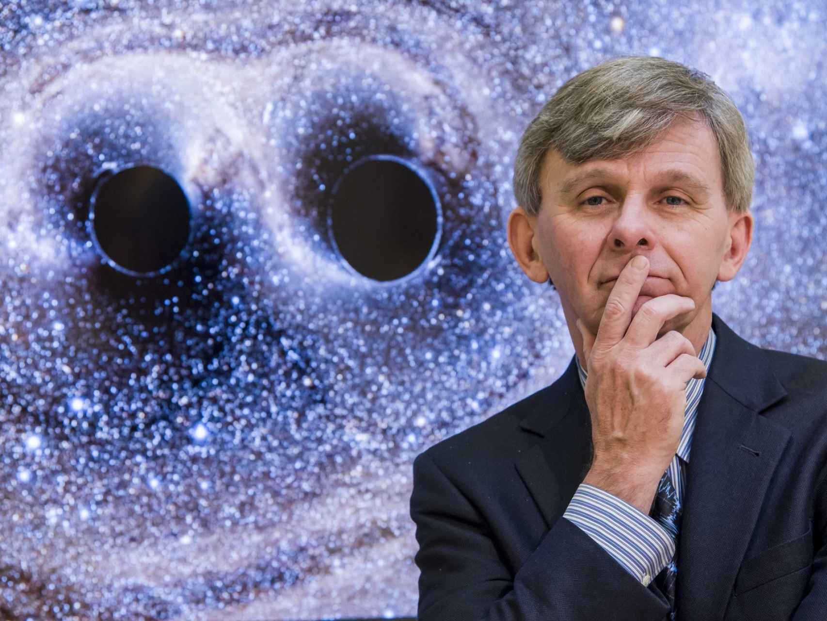 El físico David Reitze junto a dos agujeros negros.