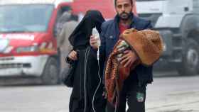 Un hombre lleva a un bebé con un gotero mientras huye más hacia el interior de la zona rebelde de Alepo.