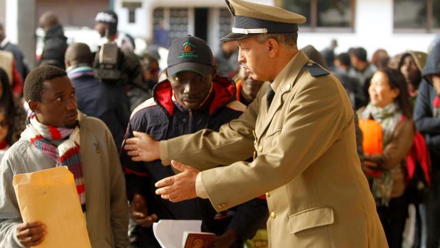 Un policía marroquí habla a un migrante en la cola para regularizarse en Rabat.