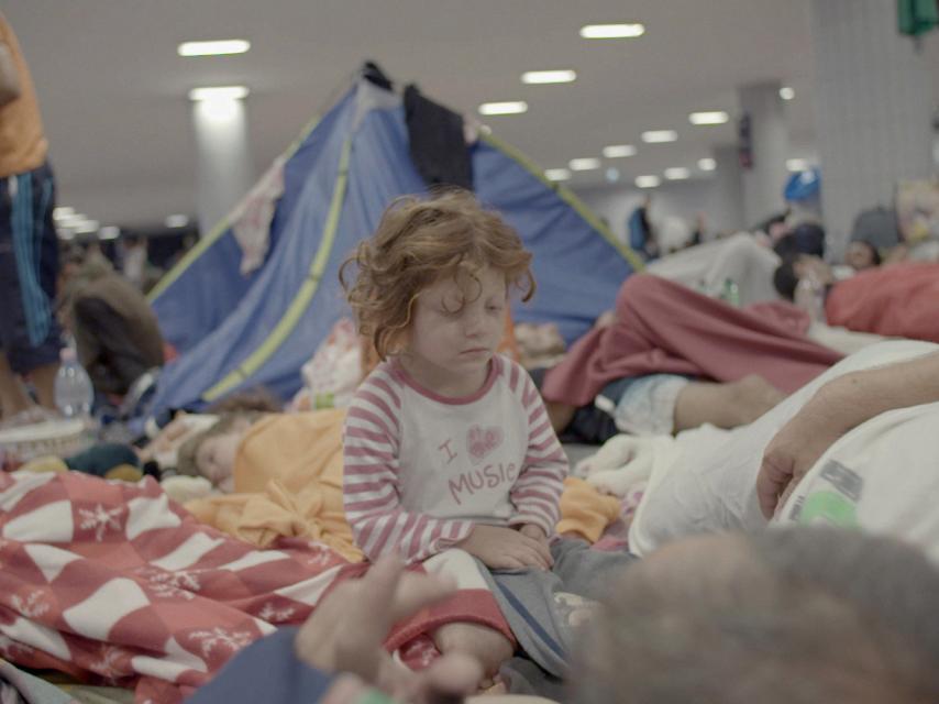 Un niño duerme en una tienda de campaña mientras espera un tren para ir a Alemania.