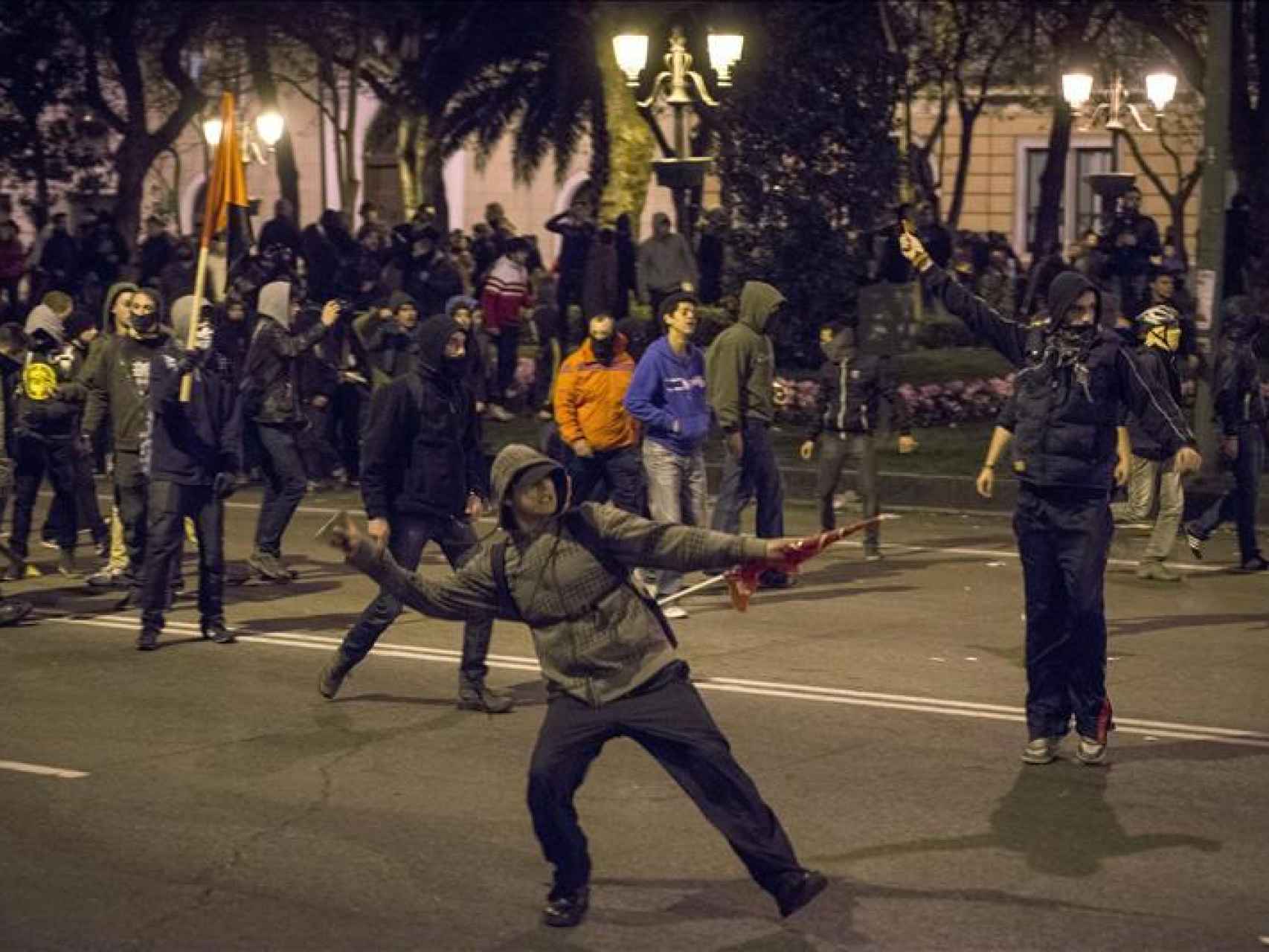 Manifestante tirando un adoquín en una revuelta.