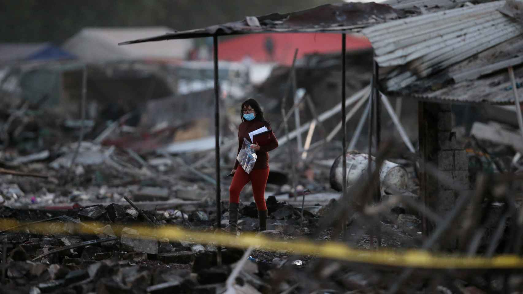 Una mujer camina entre las casas destruidas de una fábrica en México. /Reuters