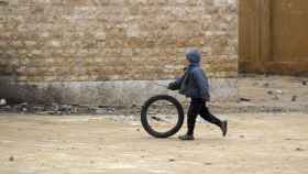 Un niño juega con una rueda en un colegio afectado por las bombas.