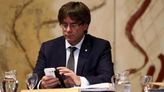 El presidente de la Generalitat, Carles Puigdemont, consulta su teléfono móvil.