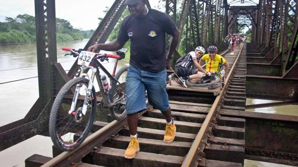 Un voluntario ayuda a los corredores a atravesar un puente.