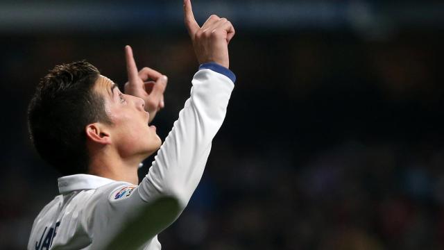 James Rodríguez celebra un gol con el Real Madrid señalando al cielo.