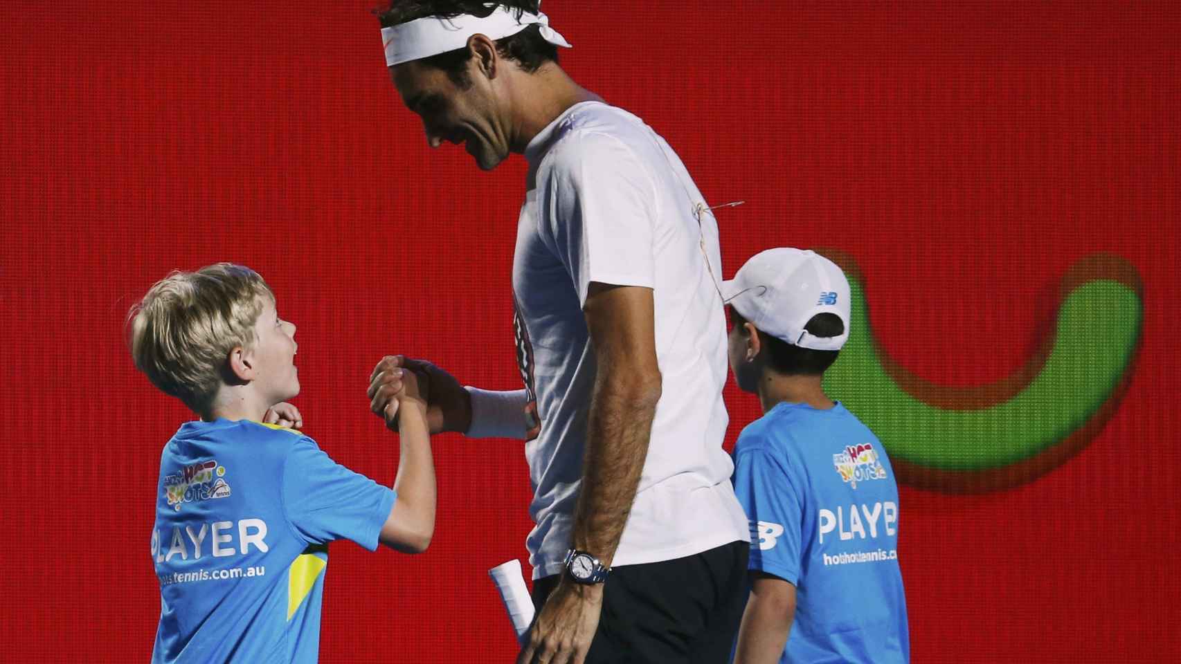 Roger Federer da la mano a un niño.