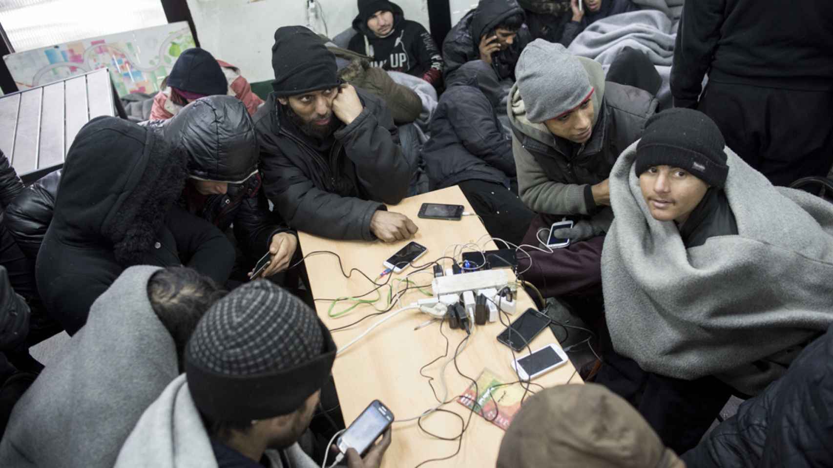 Un grupo de refugiados cargan sus móviles en el centro Aid Miksalište.