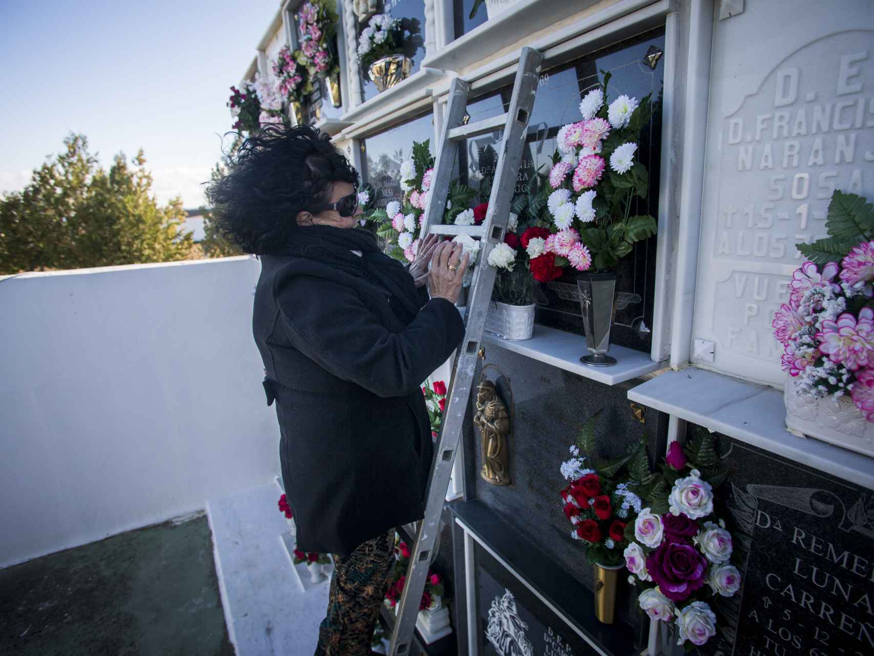 Sofía Benítez-Cubero poniendo flores a su tía Antonia Reguera, la persona que la crió, en el cementerio de El Coronil (Sevilla).