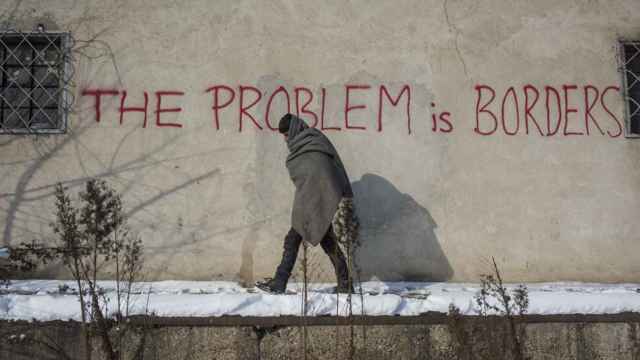 Un joven pasa junto a una pintada que dice El problema es la frontera, Belgrado, Serbia.