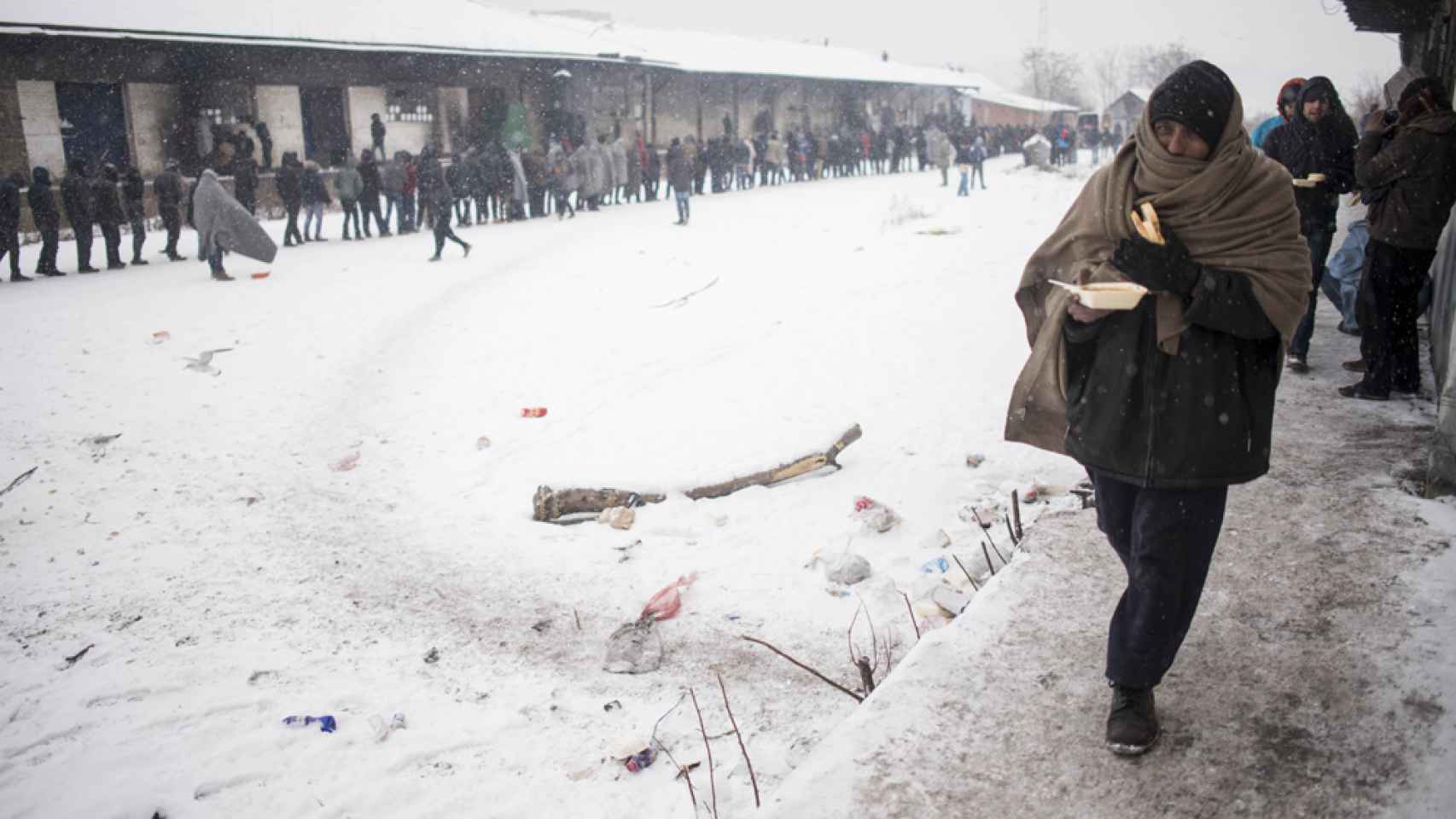 Un hombre tapado con una manta se dirige a uno de los almacenes situado detrás de la estación de tren de Belgrado, Serbia, para refugiarse de la nevada y de las bajas temperaturas.