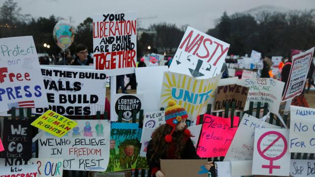 Una niña posa junto a un muro de carteles en protesta contra Trump, en Washington.