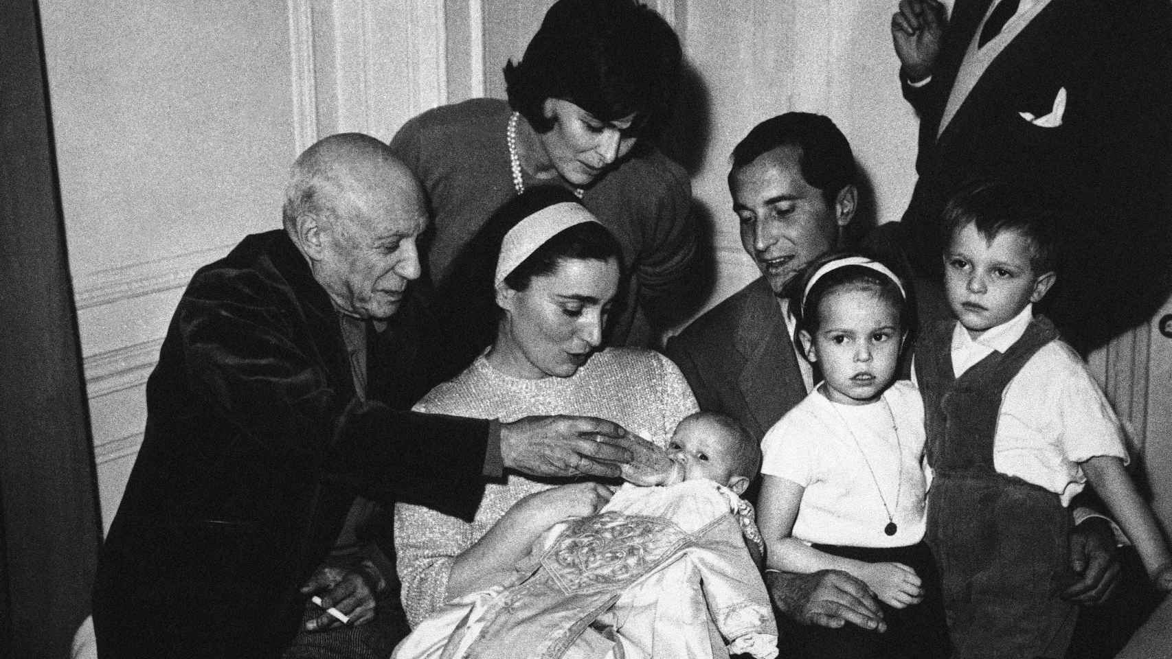Pablo Picasso, a la izquierda, dándole el biberón a su ahijada, Paola Dominguín, en su bautizo en Cannes junto al resto de la familia.