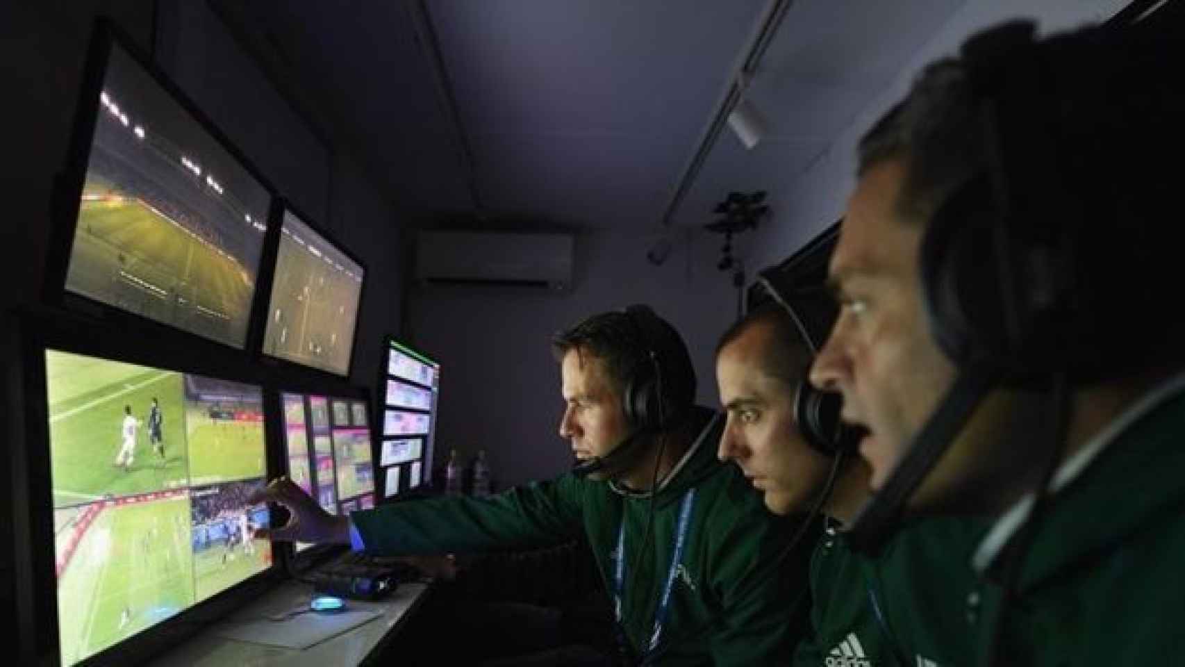Árbitros de la FIFA consultan en la TV las jugadas de un partido de fútbol.