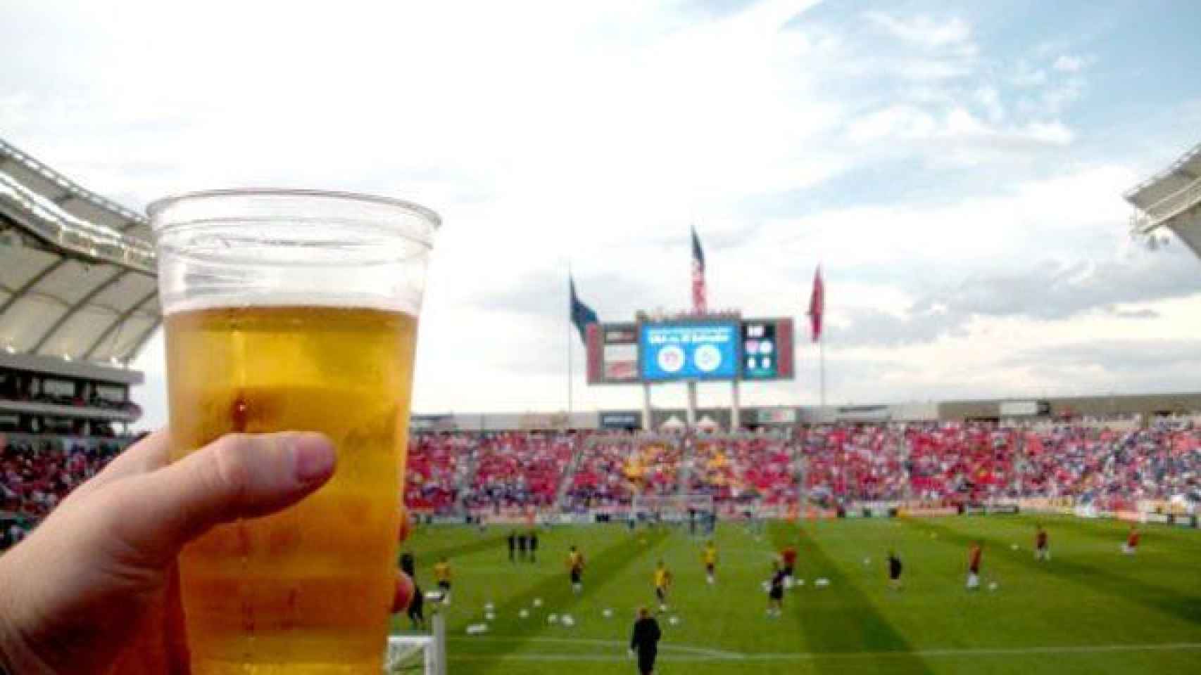 Un aficionado bebe una cerveza en un estadio de fútbol.