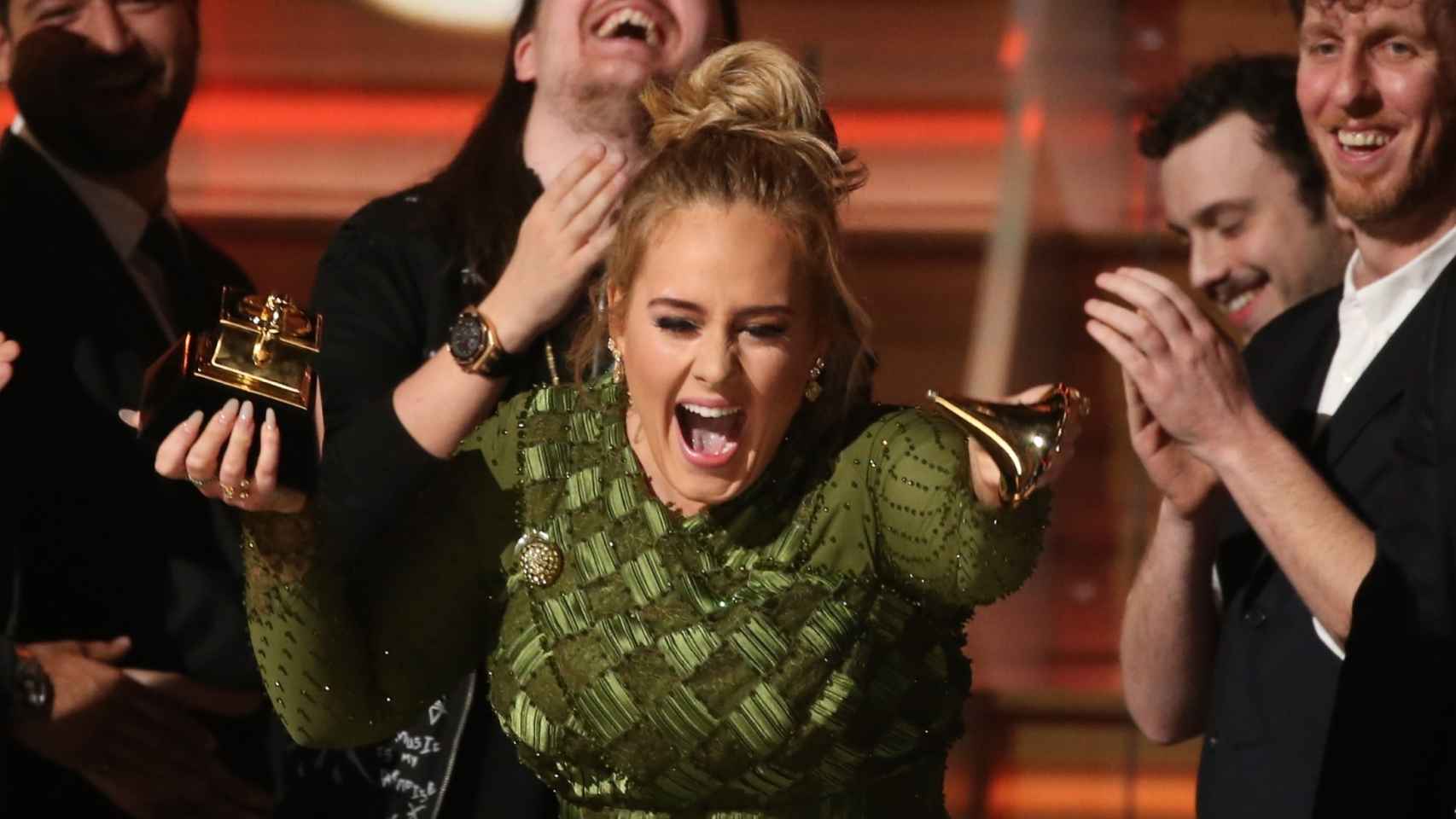 Momento en el que Adele enseña a Beyoncé el galardón partido.