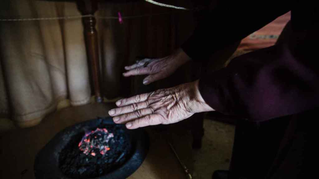 Una mujer se calienta las manos en un brasero de picón en Sevilla