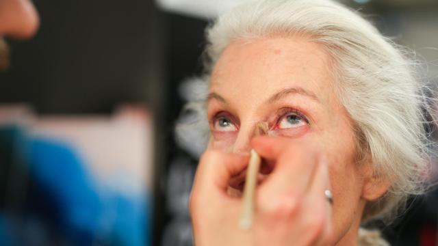 Una mujer mayor se prepara para un desfile de modelos.