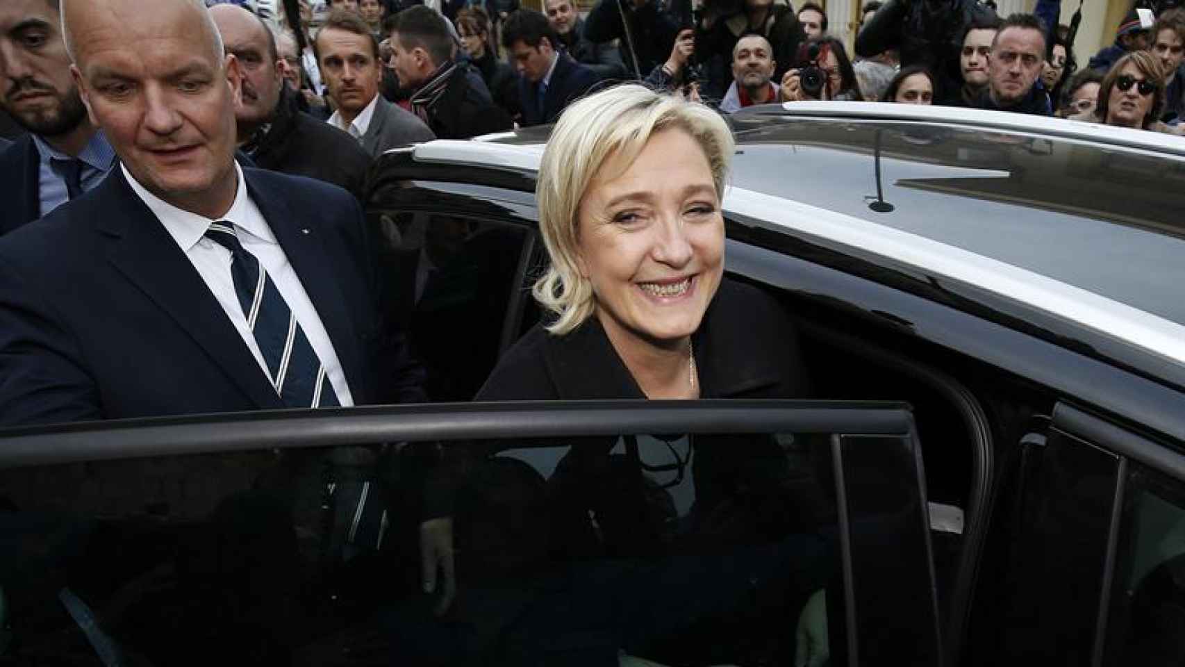 Le Pen sube al coche protegida por Thiérry Légier en un acto de campaña este febrero.